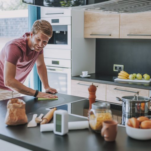 fröhlicher Mann putzt seine Küche nach dem Kochen