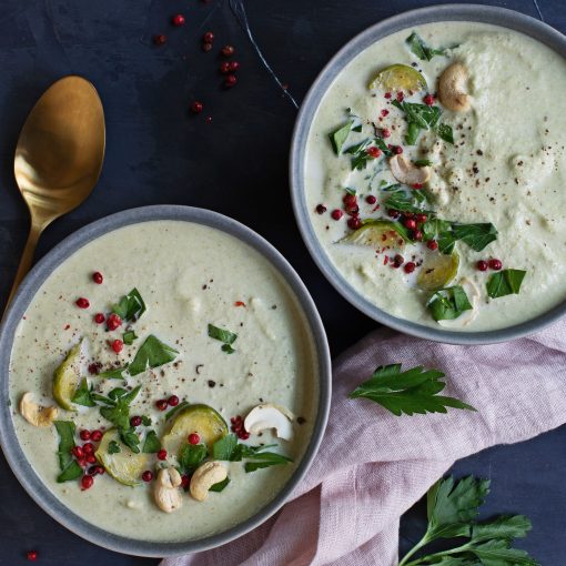 Rosenkohl Dattel Cashew suppe in grauer Schüssel und goldenem Löffel