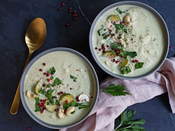 Rosenkohl Dattel Cashew suppe in grauer Schüssel und goldenem Löffel